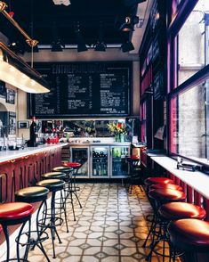 the interior of a restaurant with tables, stools and menu boards on the wall