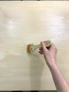 a person using a paint brush on a piece of wood