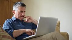 a man sitting on a couch using a laptop computer