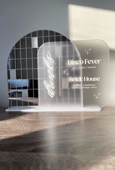 a clear glass plaque sitting on top of a wooden table next to a mirror wall