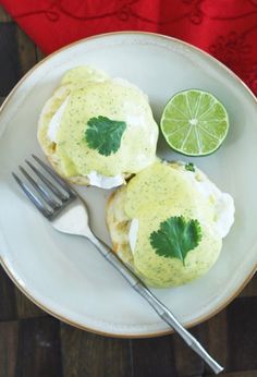 two food items on a white plate with a fork and lime wedged in the middle