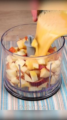 someone pouring cheese into a food processor filled with fruit