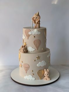 a three tiered cake with balloons and animals on the top is decorated in pastel colors