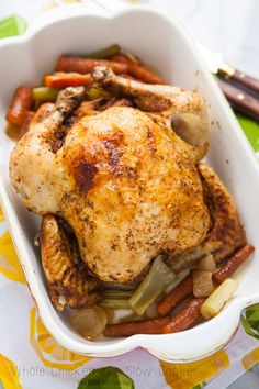 a close up of a chicken in a casserole dish with carrots and celery