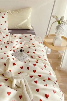 an unmade bed with red hearts on it