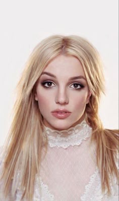 a woman with long blonde hair wearing a white shirt and posing for a photo shoot