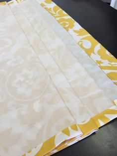 four pieces of fabric laid out on a table with yellow and white designs in the background