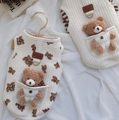 two baby bibs with teddy bears in them on top of a white bed sheet