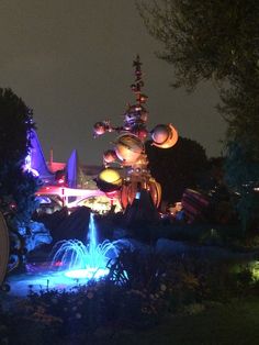 an amusement park lit up at night with lights and water fountains in the foreground