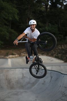 a man is doing tricks on his bike at the skateboard park while wearing a helmet