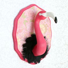 a pink and black flamingo in a pink case on a floral wallpapered background