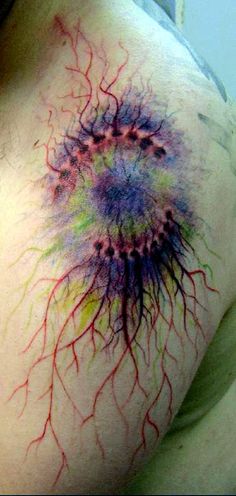 the back of a person's neck with colored ink splatters on it