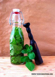 a glass bottle filled with green leaves next to a pepper shaker