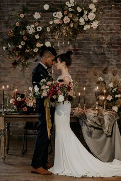 a bride and groom standing next to each other in front of a table with candles