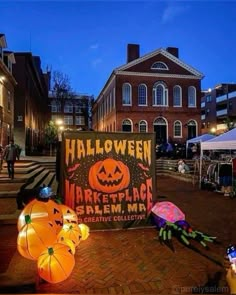 halloween decorations on the ground in front of an old brick building at night with people walking by