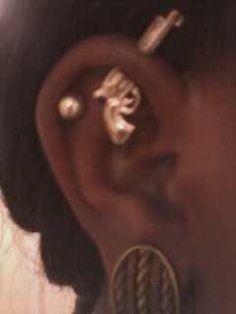 a close up of a person's ear with some piercings on it and other things in the background