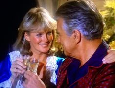 an older man and woman are holding champagne glasses in front of each other while smiling