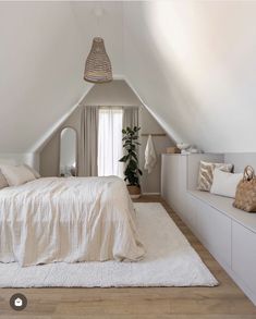 an attic bedroom with white walls and wooden flooring is furnished with natural materials such as linens, pillows and blankets