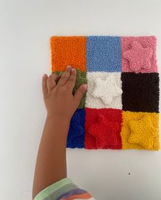 a child's hand is touching the colorful squares that are on top of each other