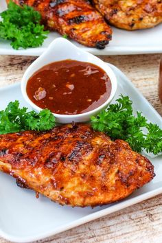 grilled chicken with sauce and parsley garnishes on two white plates