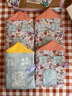 two small houses made out of fabric on top of a checkered tablecloth with pictures