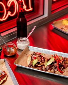 two trays filled with food sitting on top of a table next to a bottle