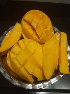 a metal plate topped with sliced mangoes on top of a table