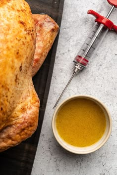 a whole chicken sitting on top of a wooden cutting board next to a bowl of oil