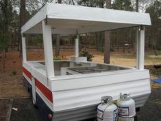 an old camper converted into a mobile home with propane tanks on the ground