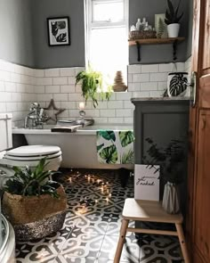 a bathroom with a toilet, bathtub and plants in the window sill on the floor