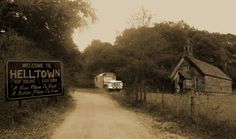 an old truck is parked on the side of a road next to a sign that says helltown