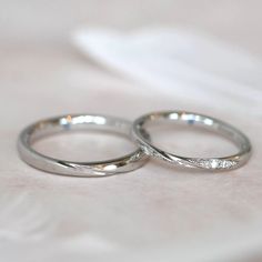 two wedding rings sitting on top of a white cloth