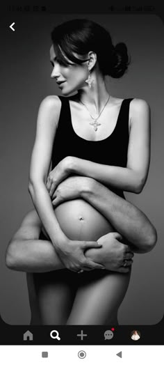 black and white photograph of a pregnant woman holding her baby bump up to her stomach