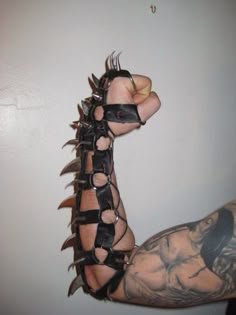 a man's arm with tattoos and spikes on it, holding up his arm