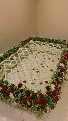 a large white cake with red and green flowers on the top is sitting in a room