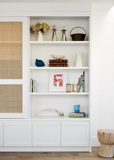 a white bookcase filled with books and vases