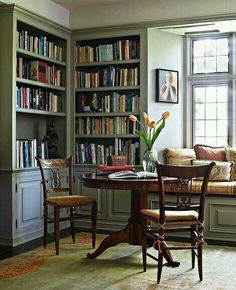 a room with a table, chairs and bookshelves