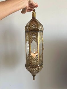 a person is holding an ornate brass lantern with a candle inside it and the light shining