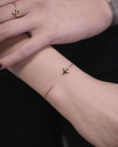 a woman's arm with a small airplane tattoo on the left side of her wrist