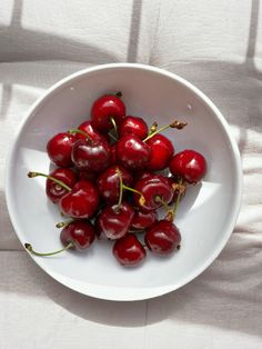 a white bowl filled with cherries on top of a table