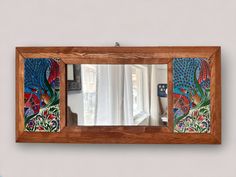 a mirror that is sitting on top of a wooden frame with peacocks painted on it