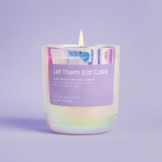 a candle that is sitting in front of a purple background with the words let them eat cake on it