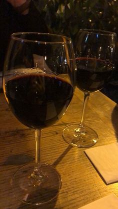 two glasses of wine sitting on top of a wooden table