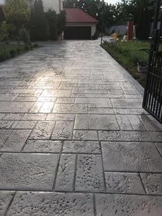 an empty driveway in front of a house with the sun shining on it's side