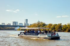 a tour boat with passengers going down the river in front of a cityscape