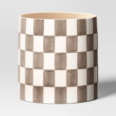 a white and brown checkered coffee cup on a gray background with the lid off