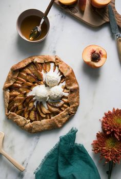 an apple pie is sitting on a marble counter top next to sliced apples and flowers