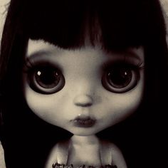 a black and white photo of a doll with big eyes