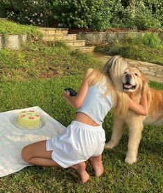 a woman kneeling down next to a dog with a cake on it's back