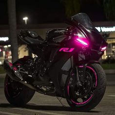 a black motorcycle with pink lights on it's front wheel and tire rims